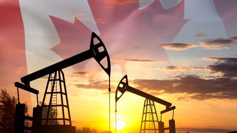 Silhouette of oil rigs against the sunset with Canada flag. Oil Industry concept